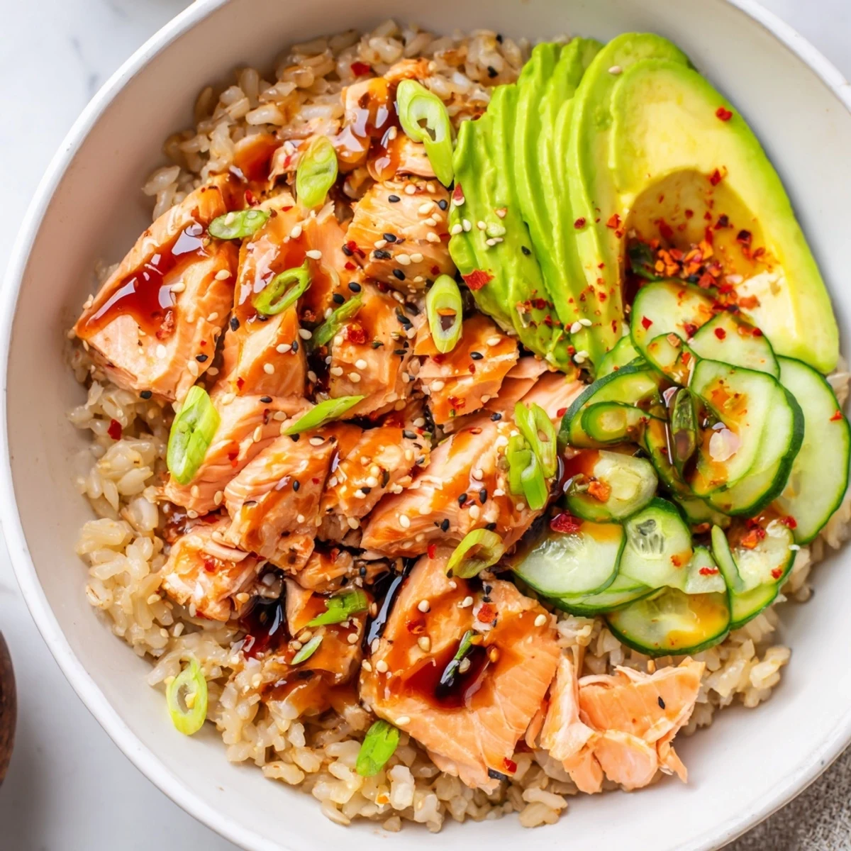 Delicious leftover salmon and rice bowl topped with fresh avocado and cucumber slices.
