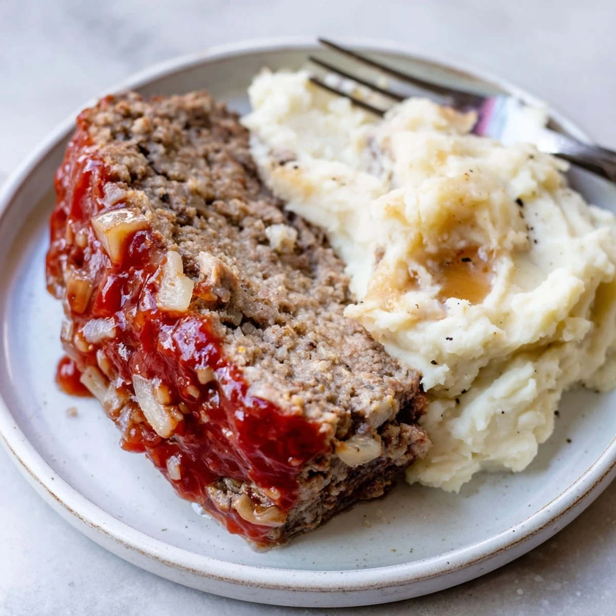 Sliced Classic Meatloaf paired with buttery mashed potatoes and a vibrant glaze.