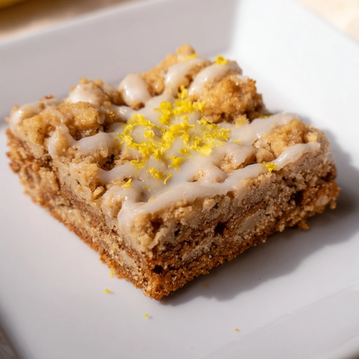 Tangy lemon glaze drizzled on spiced and tender Lemon-Glazed Gingerbread Crumble Bars, inviting a sweet bite.