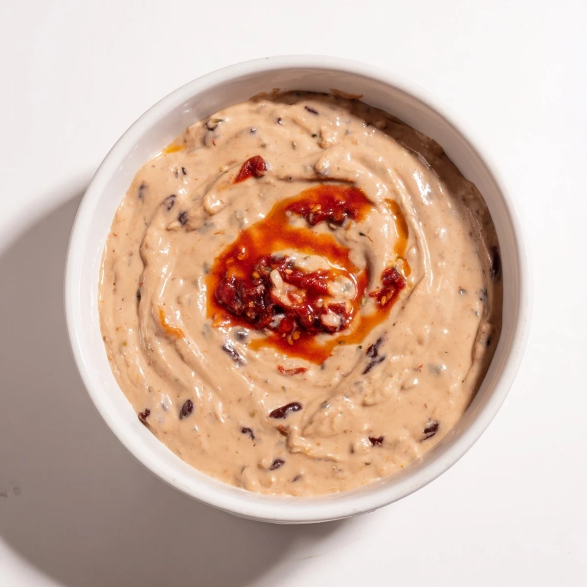 Creamy Spicy Black Bean Dip, ready to be scooped up with crispy tortilla chips, is vibrant.