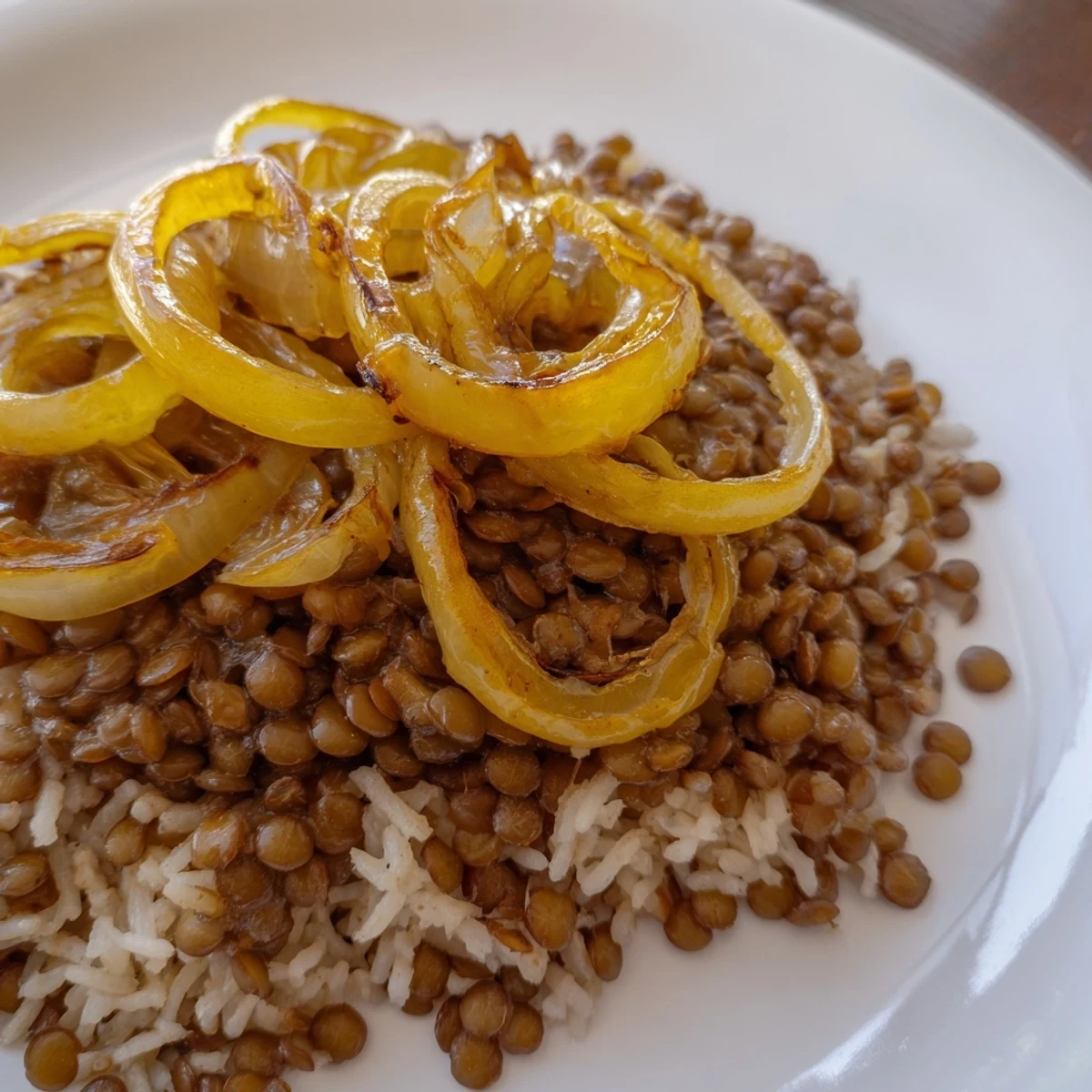 Enjoy the comforting aroma of Lebanese Mjadra, a vegan dish of lentils, rice, spices, and onions.