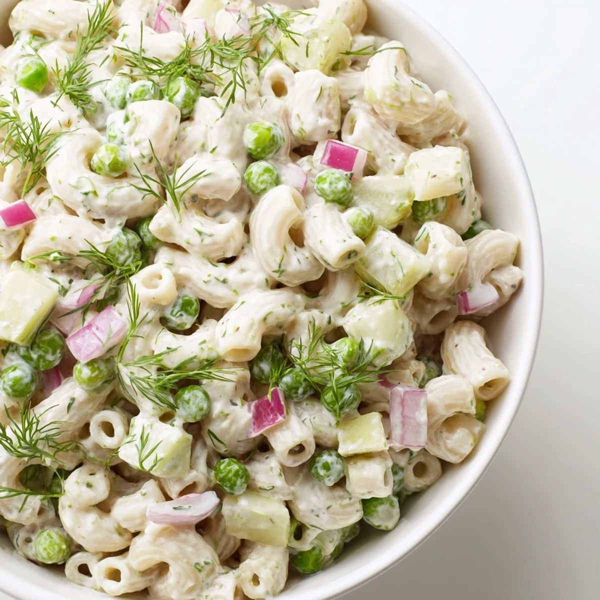 A close-up of dill pickle pasta salad with creamy coating, ideal for a picnic or potluck.