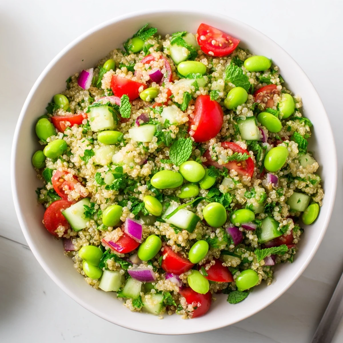 Healthy Edamame and Quinoa Salad tossed in a zesty lemon dressing, showcasing juicy cherry tomatoes and crisp cucumber for a refreshing, protein-rich lunch.