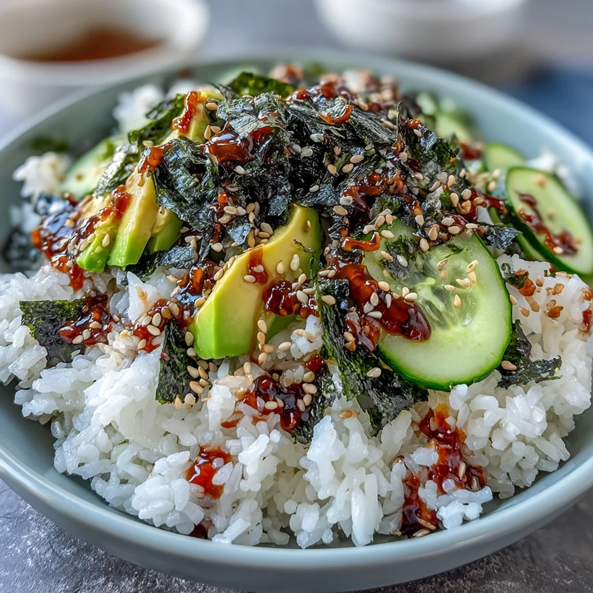 Colorful deconstructed sushi bowl featuring fluffy rice, fresh vegetables, savory nori, and a zesty spicy mayo drizzle, perfect for lunch or dinner.