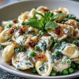 A close-up of delightful lemon ricotta pasta dish garnished beautifully with mint and cheese.