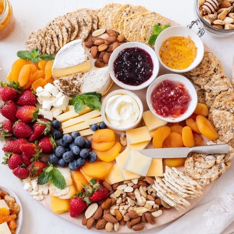 A colorful jam-infused brunch board featuring fresh fruits, cheeses, and artisan breads.  