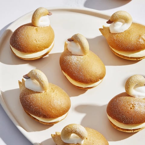 Golden mini pastries shaped like elegant swan, filled with vanilla cream—perfect dessert.