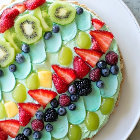 Vibrant Under the Sea: Mermaid Tail Fruit Pizza with colorful fruit scales on creamy frosting.