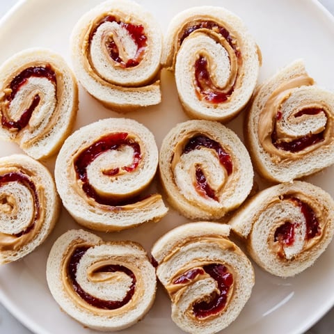 Quartered PB&J pinwheel rolls, a colorful snack, ready to eat with peanut butter and jelly swirls.