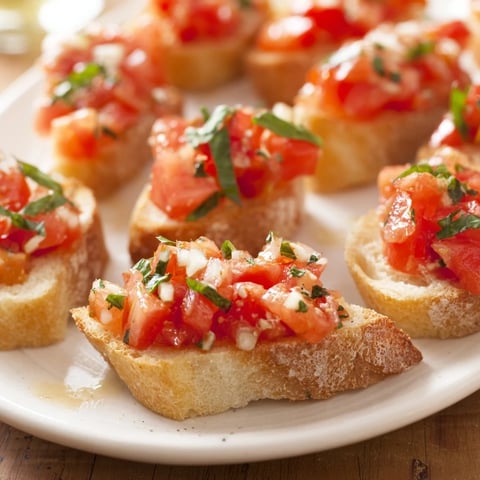 Golden, crispy Bruschetta toasts arranged diagonally, with vibrant tomato and basil toppings, perfect for sharing.