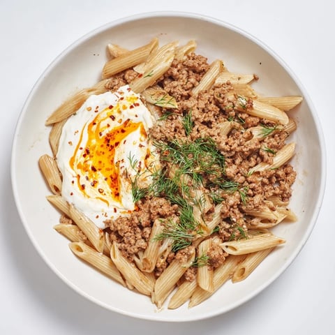 Steaming Turkish Pasta with Ground Turkey, garnished with fresh herbs and a vibrant paprika butter drizzle.