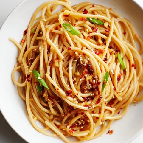 Steaming bowl of Garlic Chili Oil Noodles, perfectly tossed with a fiery red chili sauce, ready to eat.