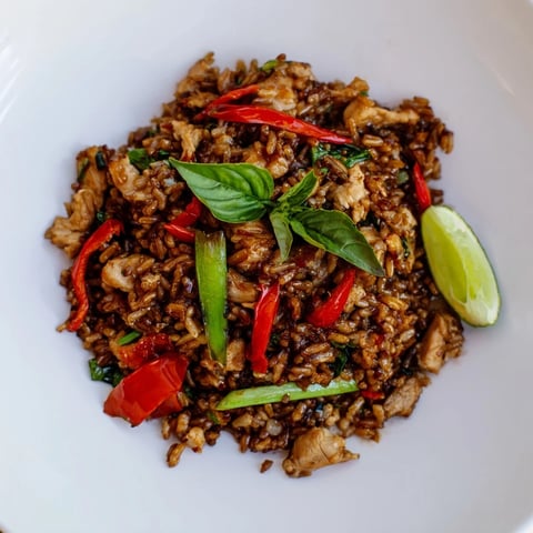 Steaming hot Thai Basil Chicken Fried Rice with vibrant chilies and fresh basil, ready to eat.