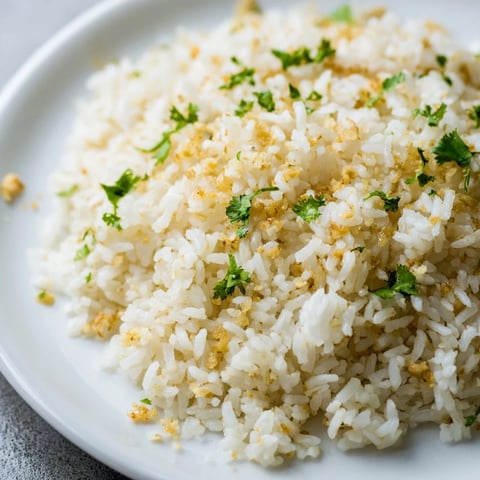 Fluffy jasmine rice garlic, a glistening side dish, served with fresh cilantro garnish and prepared in a saucepan.