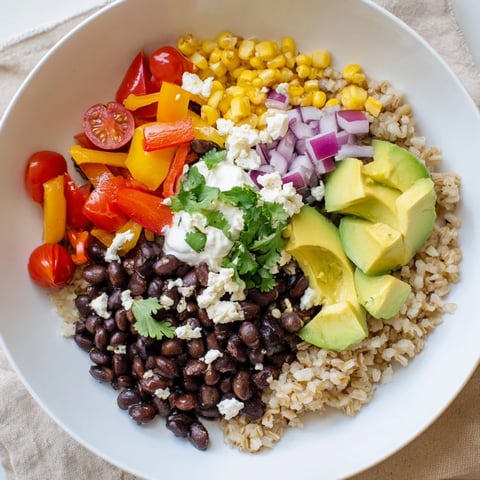 Brown rice burrito bowl with seasoned black beans, fresh veggies, and creamy toppings.