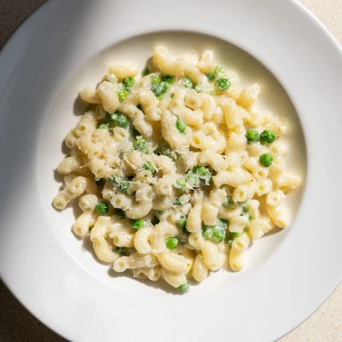 A close-up of delicious Macaroni & Peas, perfectly cooked with vibrant green peas and parmesan.