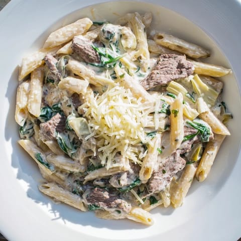 A close-up shot of the savory Steak & Spinach Artichoke Pasta Bake, cheesy and fragrant from the oven.