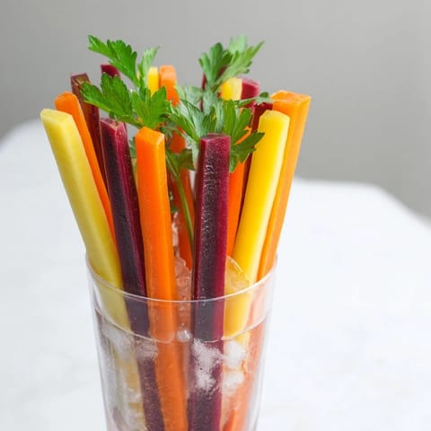 Simple Crudités: Colorful carrot sticks stand upright in chilled glasses, a refreshing appetizer.