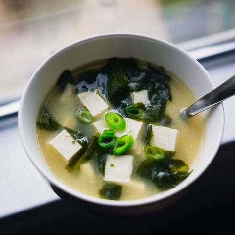 This Miso Soup With Tofu is garnished with fresh scallions, offering a comforting, healthy starter ready in just twenty minutes.