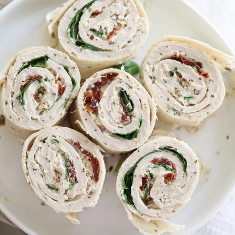Close-up of savory sun-dried tomato turkey roll-ups, ready to eat, with visible fresh spinach.