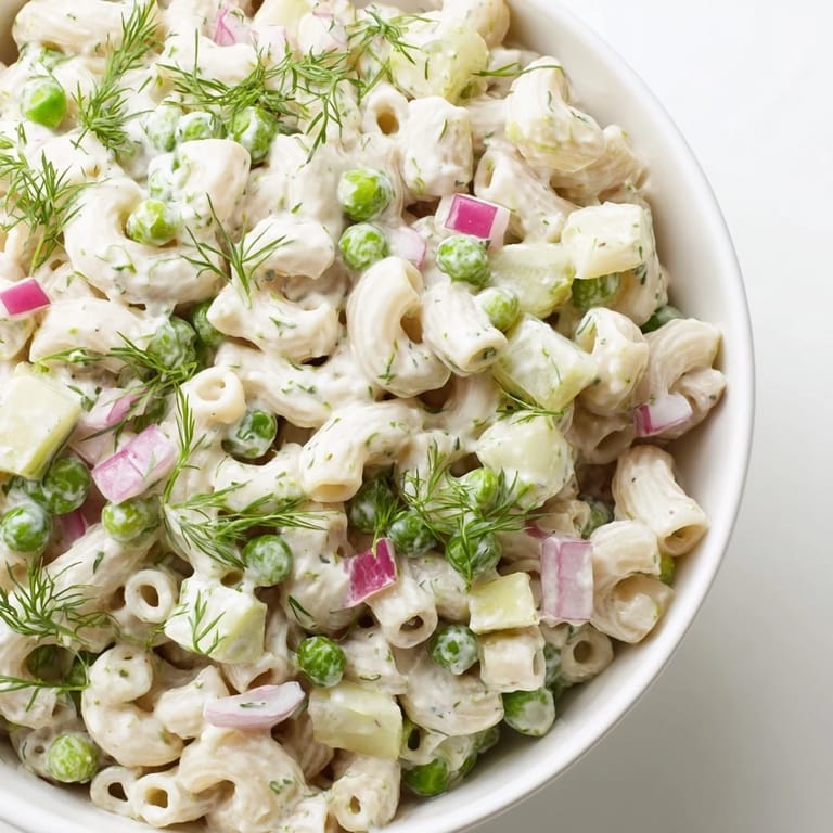 A close-up of dill pickle pasta salad with creamy coating, ideal for a picnic or potluck.