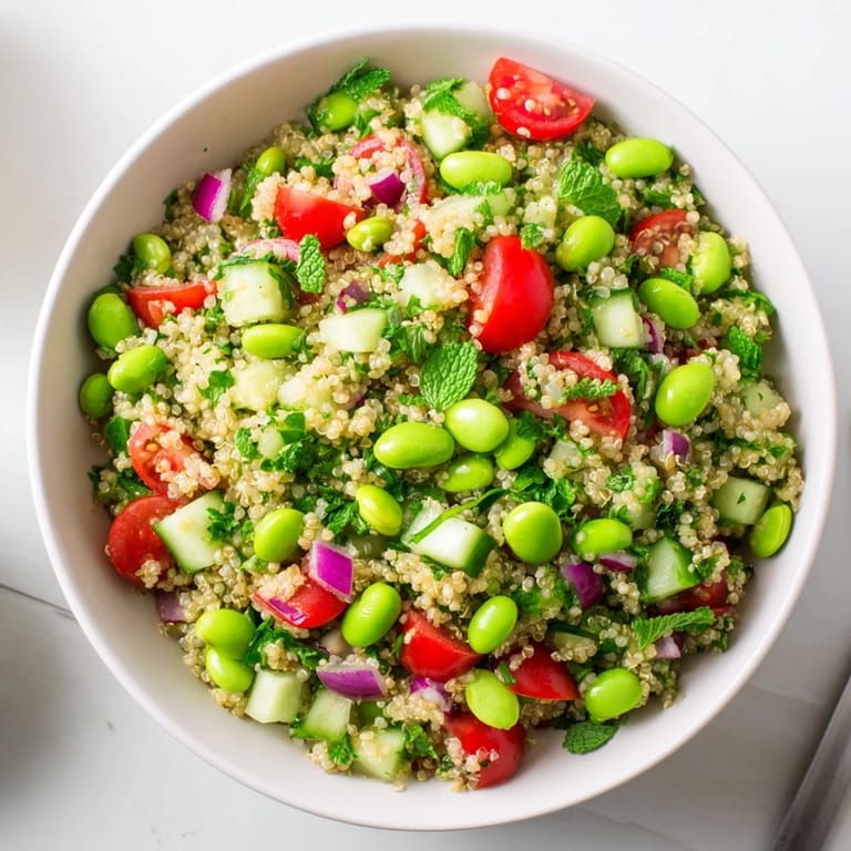 Healthy Edamame and Quinoa Salad tossed in a zesty lemon dressing, showcasing juicy cherry tomatoes and crisp cucumber for a refreshing, protein-rich lunch.