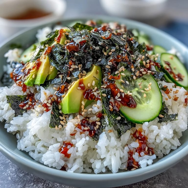 Colorful deconstructed sushi bowl featuring fluffy rice, fresh vegetables, savory nori, and a zesty spicy mayo drizzle, perfect for lunch or dinner.
