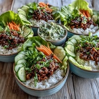 Fluffy rice topped with savory sesame turkey in sesame lettuce wrap bowls, garnished with cucumber ribbons and green onions.